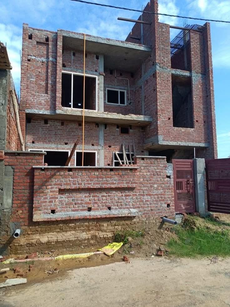 Three-storey house under construction with exposed brickwork and concrete slabs
